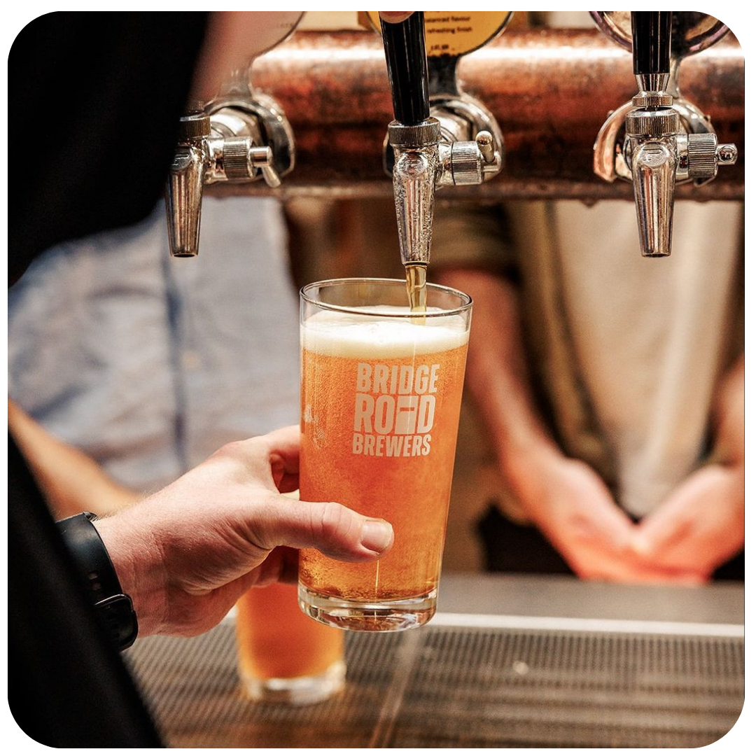 Person pouring Bridge Road Brewers beer into a glass at a bar.