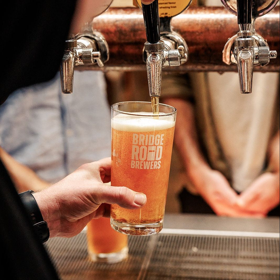 Person pouring Bridge Road Brewers beer into a glass at a bar.